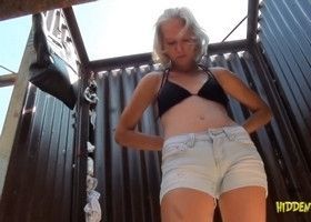 Девушка в пляжной кабинке снимает трусы и лифчик